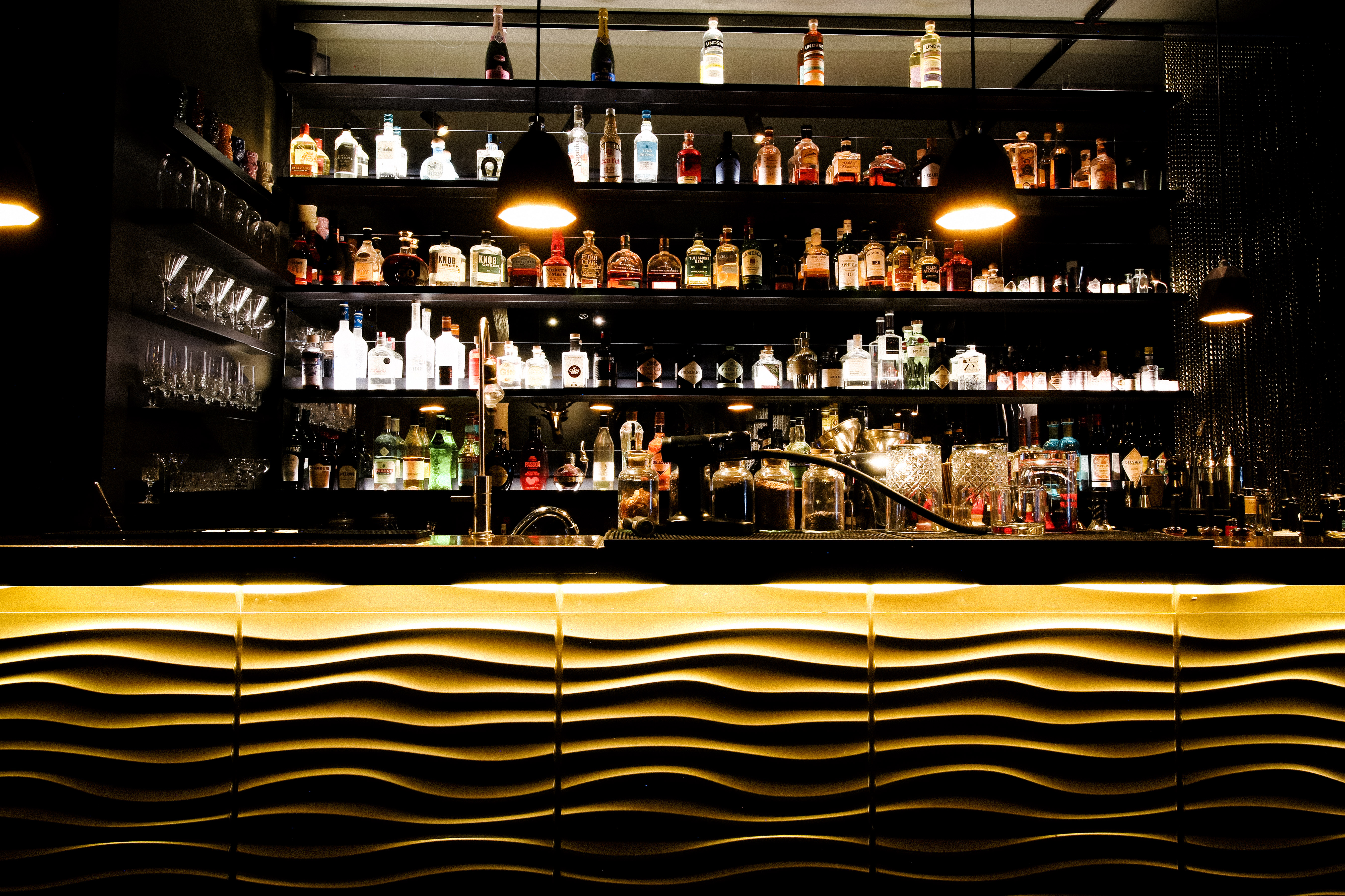 Beleuchtete Bar mit Flaschen und Gläsern.