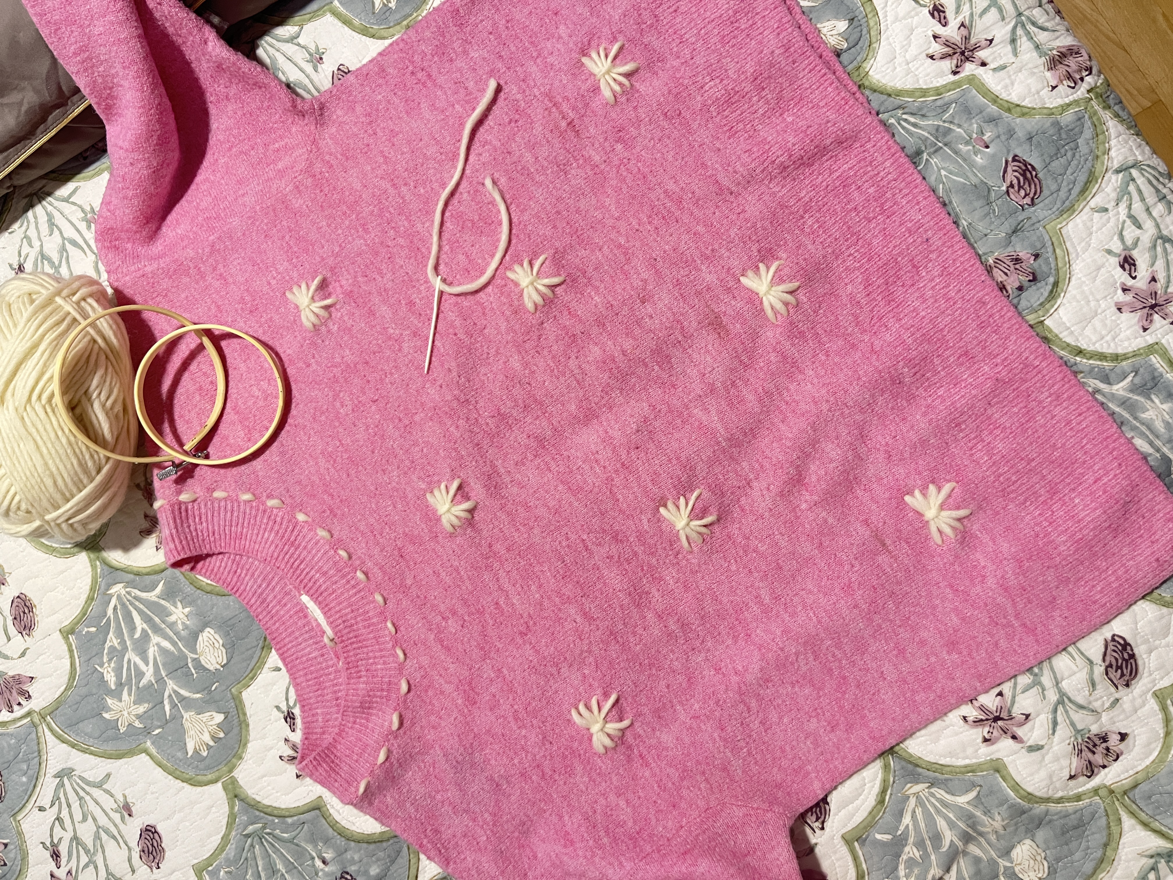 Rosa Pullover mit Stickerei, Garn und Reifen.