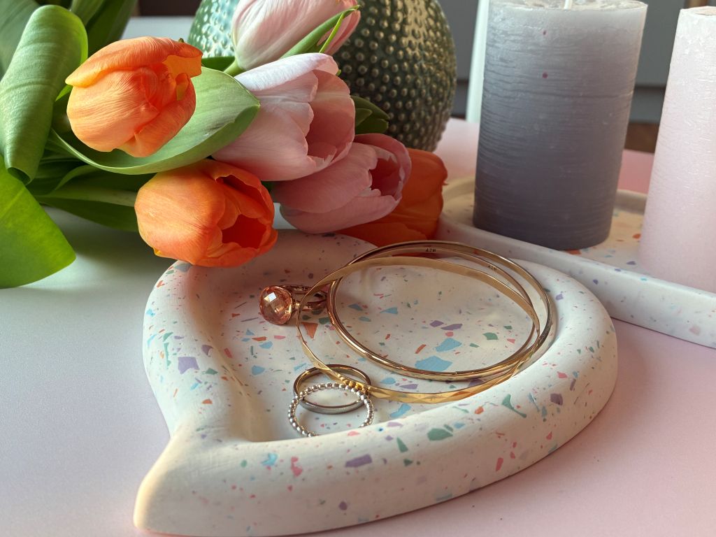 Jewelry on a dish with tulips nearby.