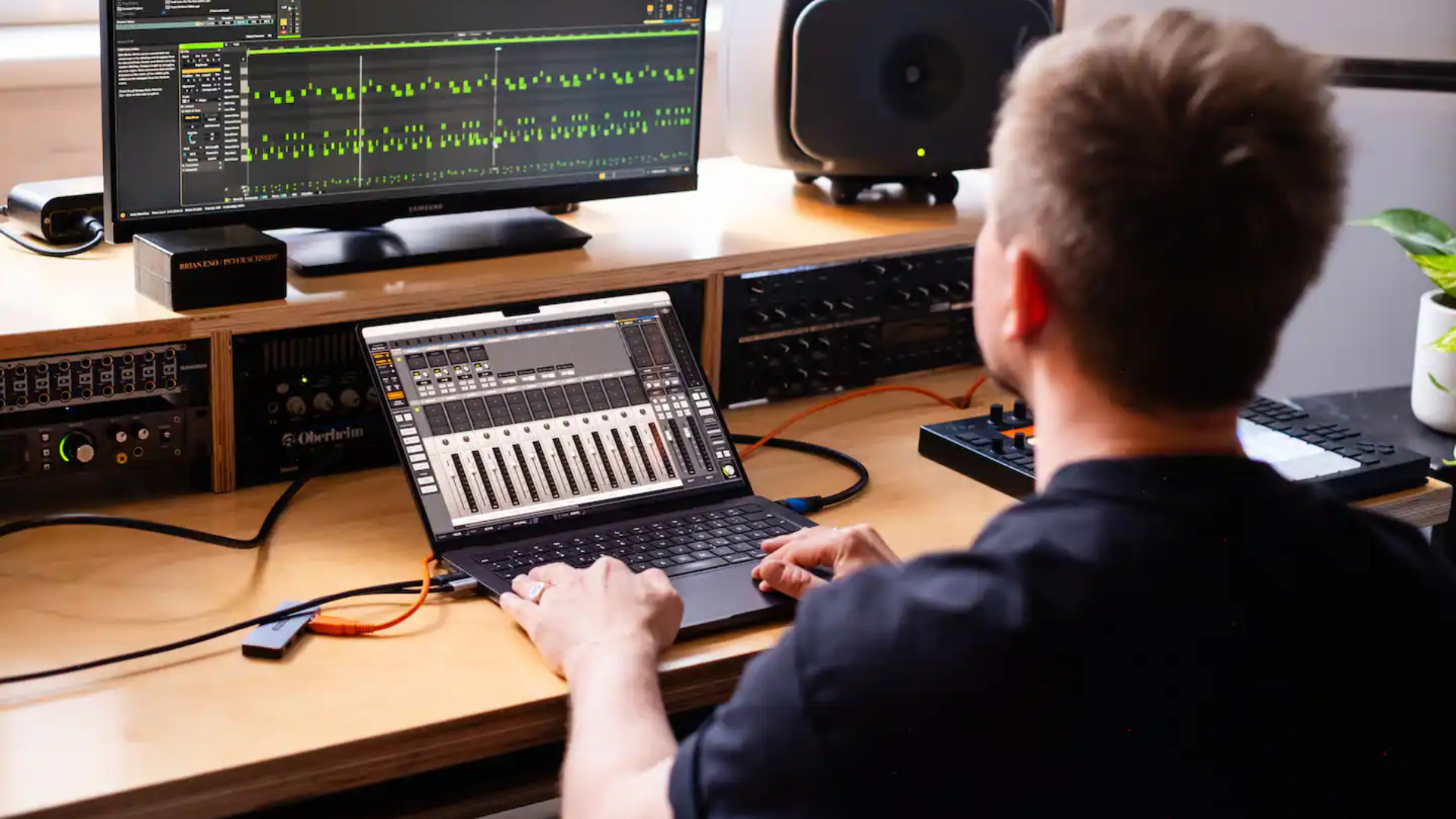 Person mixing audio on laptop in studio.