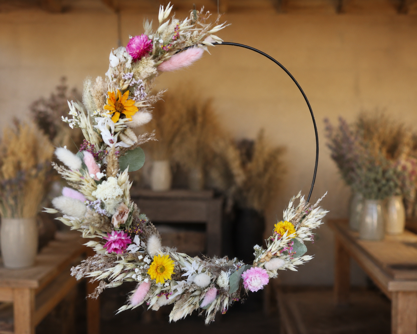 Floral hoop wreath hanging in rustic shop.