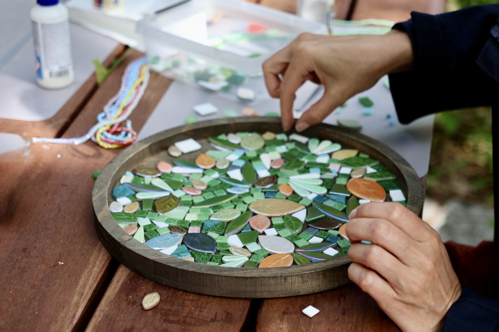 Hände machen Mosaik auf Holztisch.