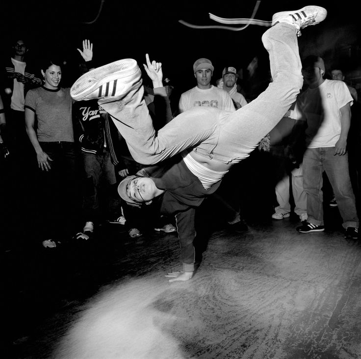 Breakdancer handstand in crowded dark space.