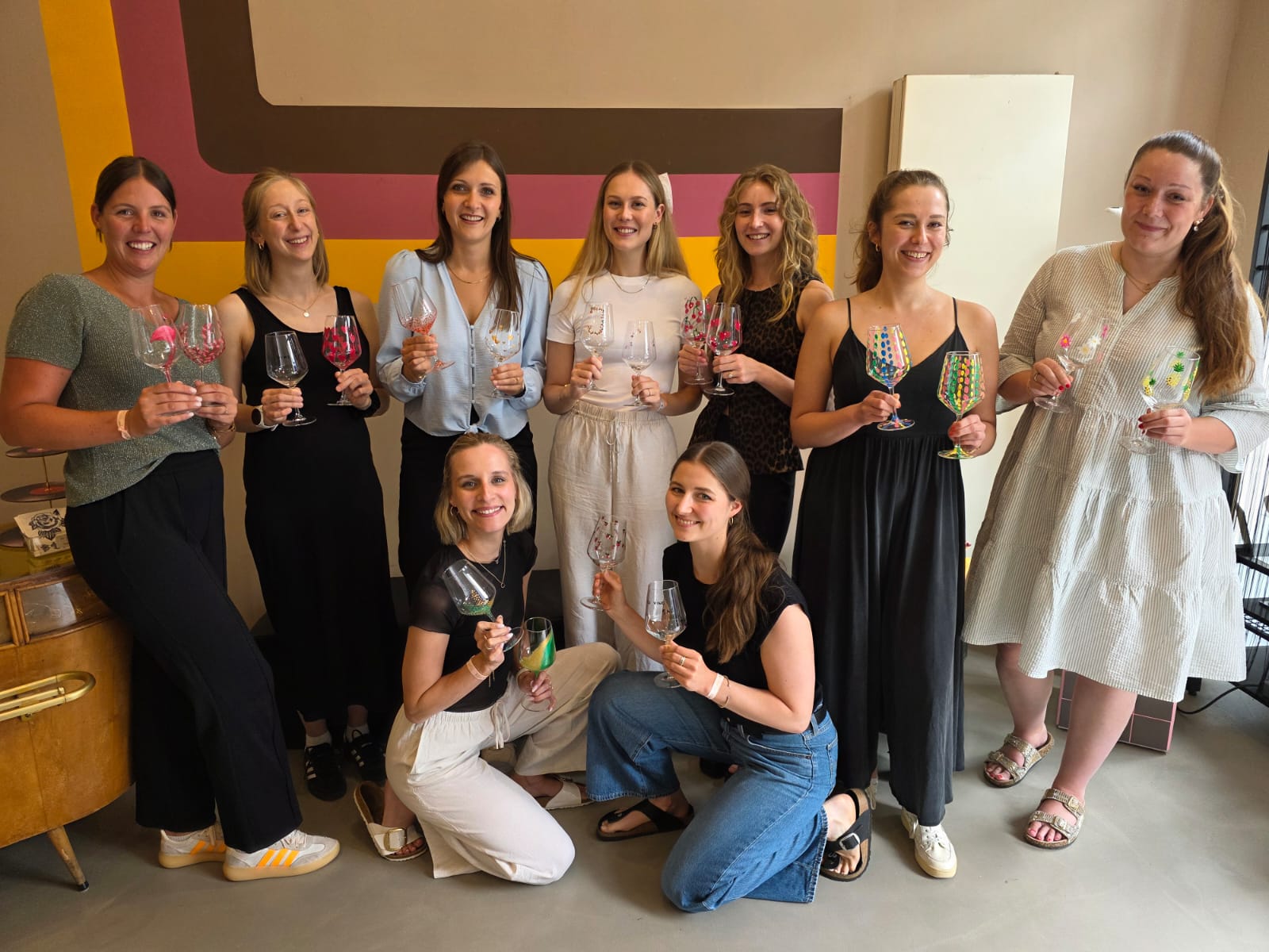 Women posing with decorated wine glasses.