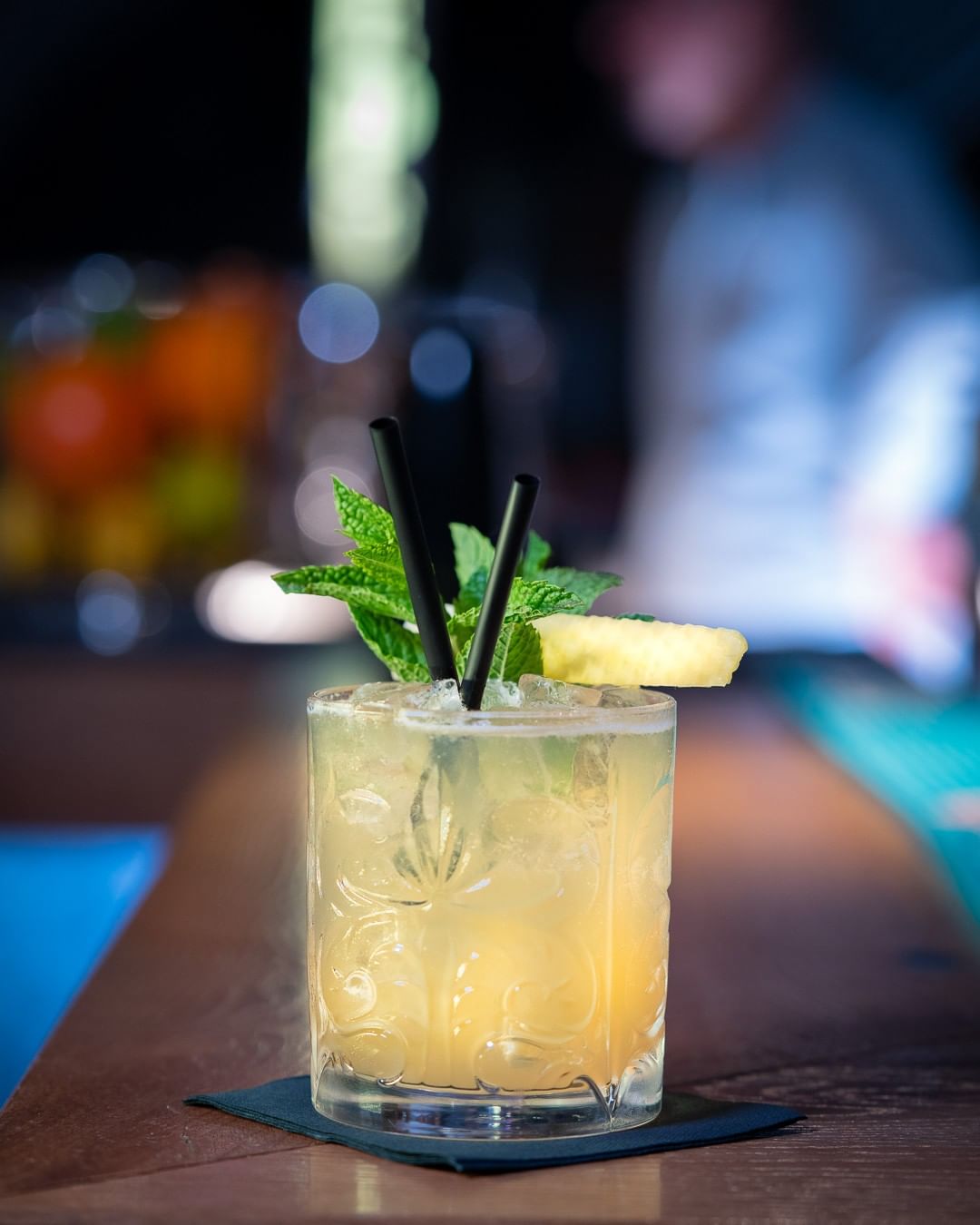 Ein Cocktail steht auf einem Tisch mit Minze und Ananas.