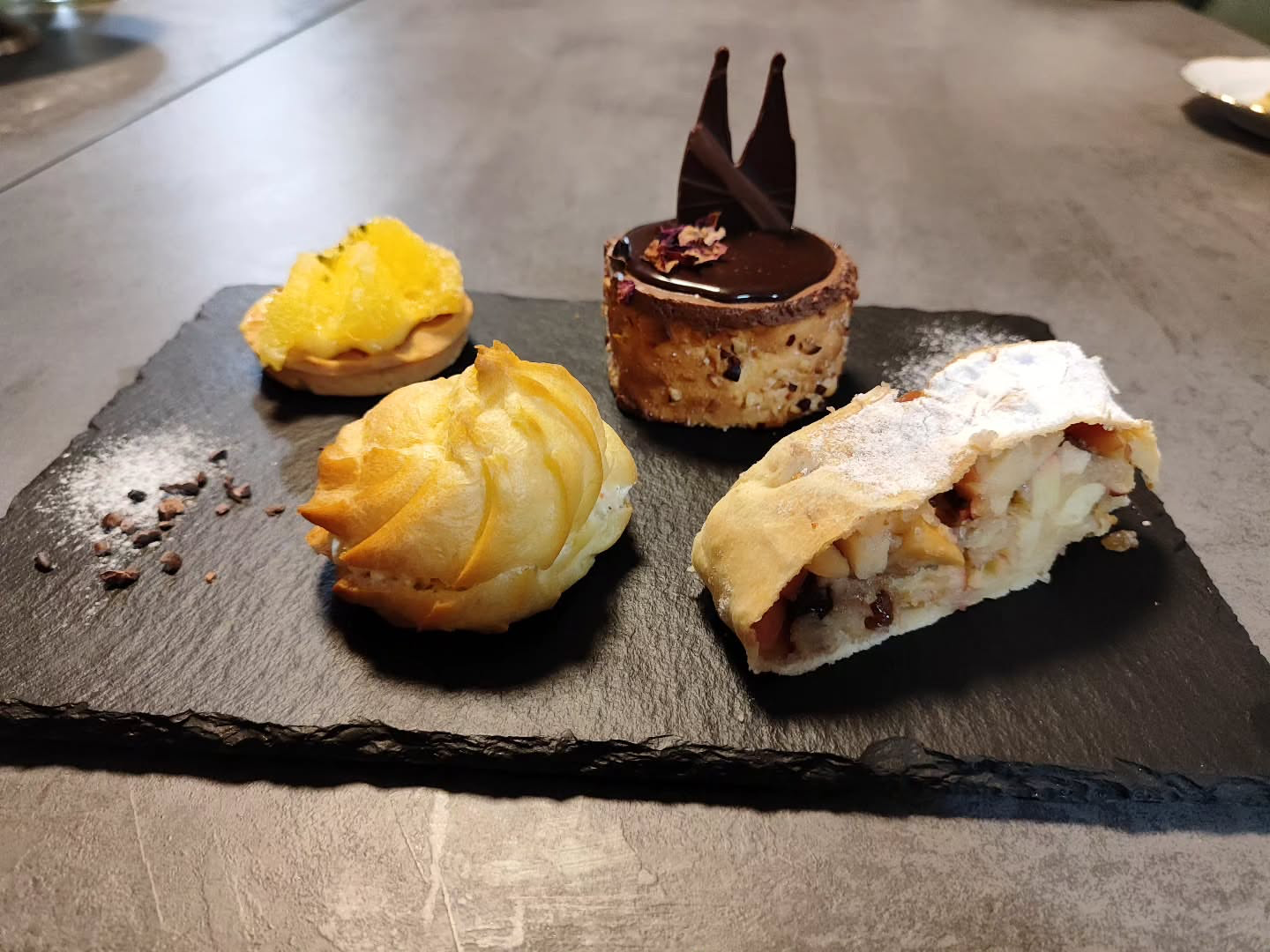 Pastries arranged on black slate plate.