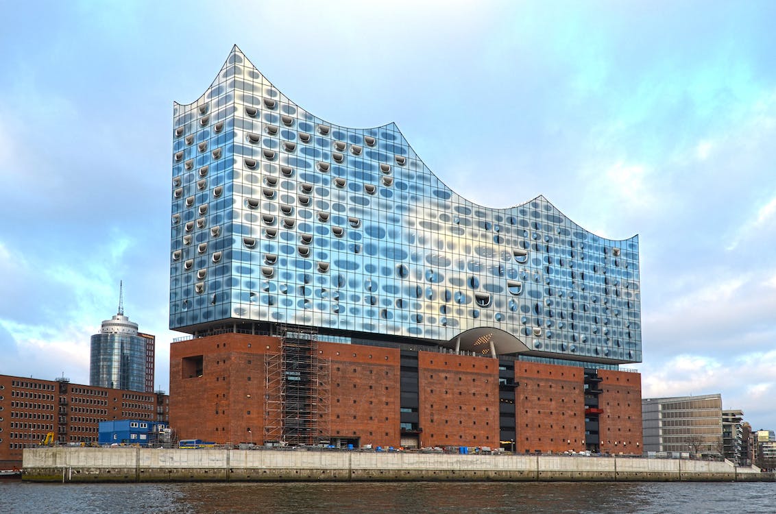 Moderne Architektur reflektiert Himmel, steht am Wasser.