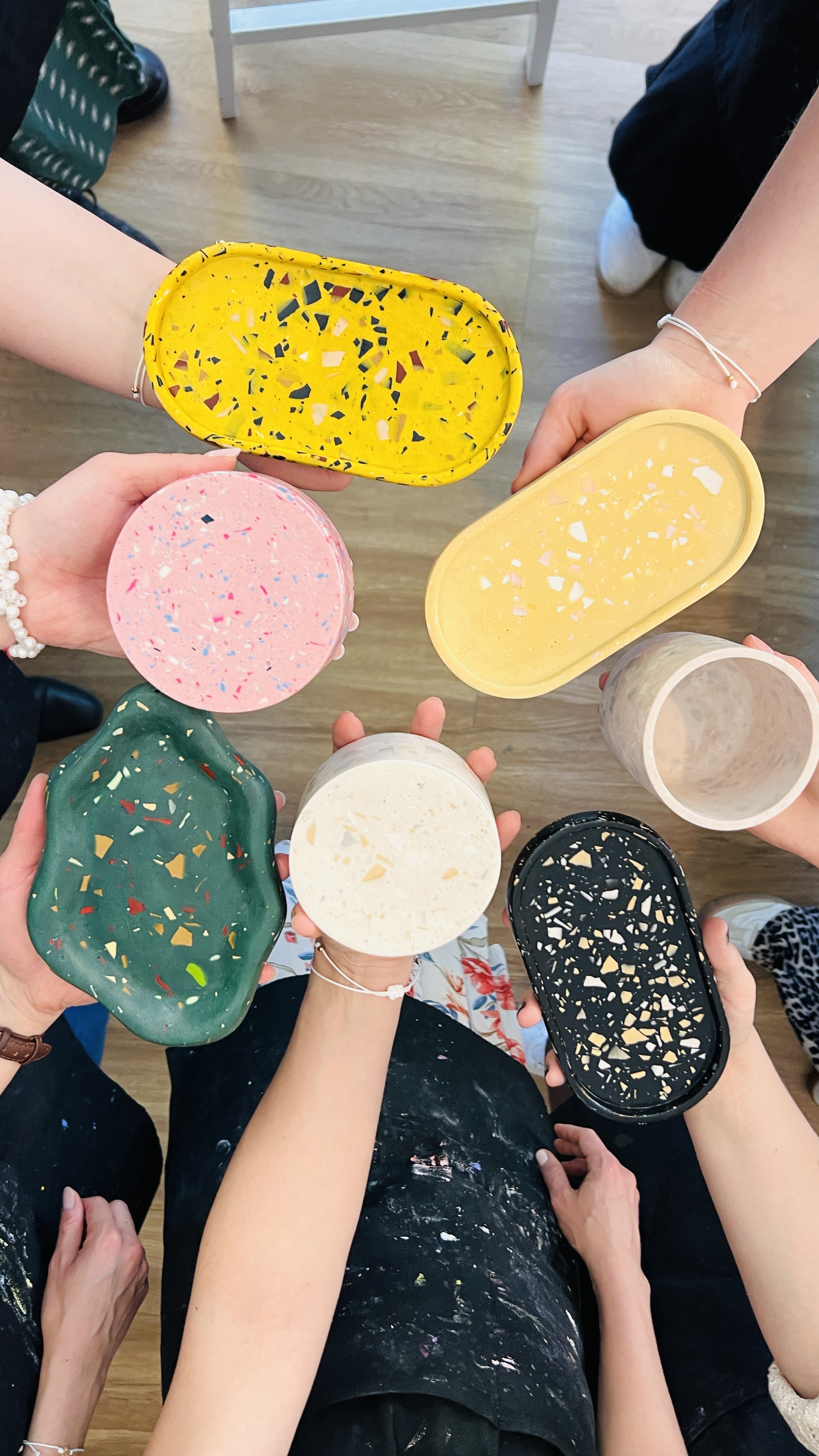 Hands holding colorful terrazzo coasters indoors.