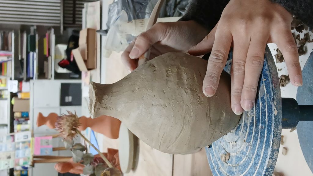 Hände formen Tonvase im Studio.