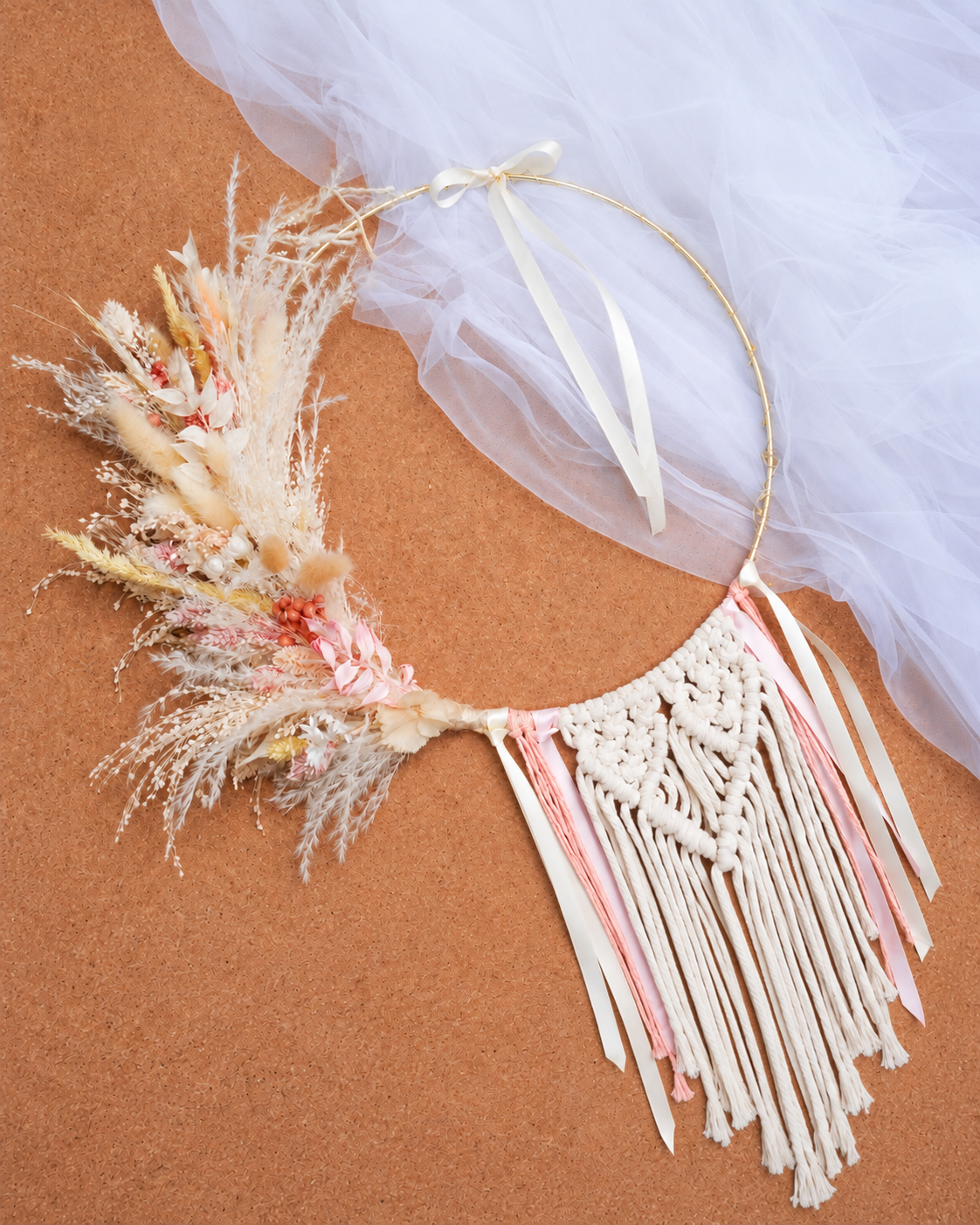 Dreamcatcher with dried flowers on fabric background.