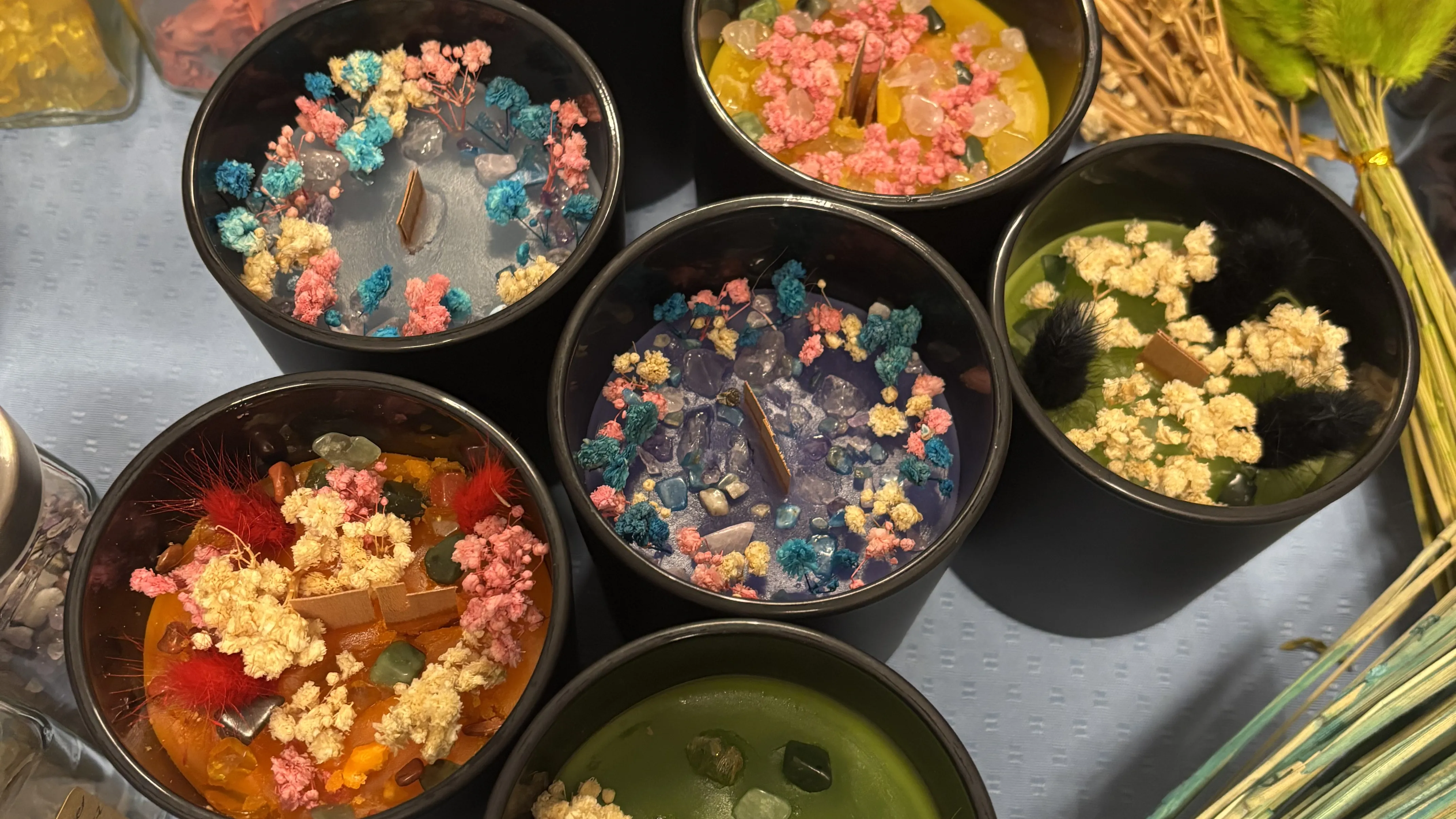 Colorful candles decorated with dried flowers.