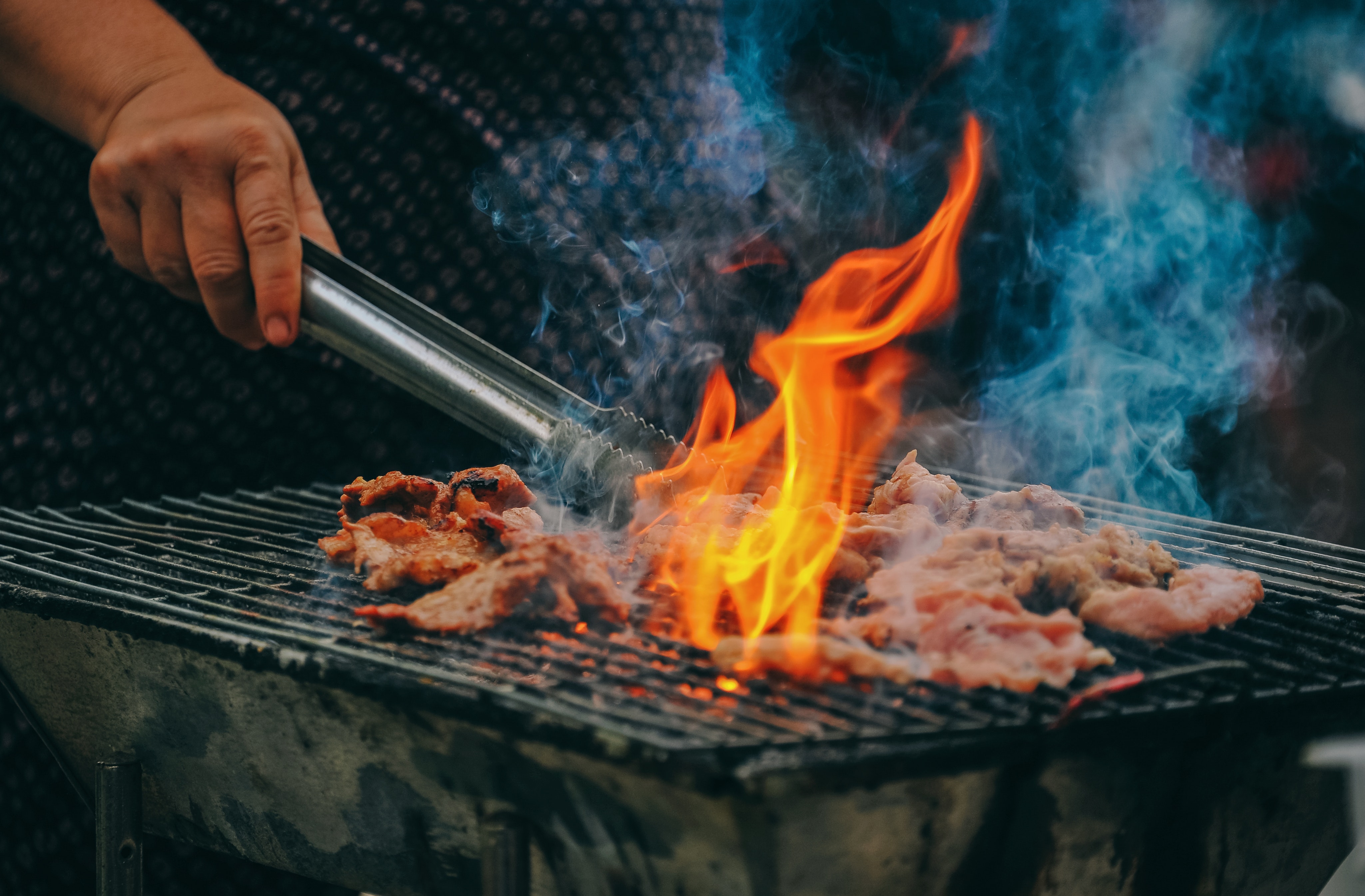Meat is cooked over an open fire on a grill.