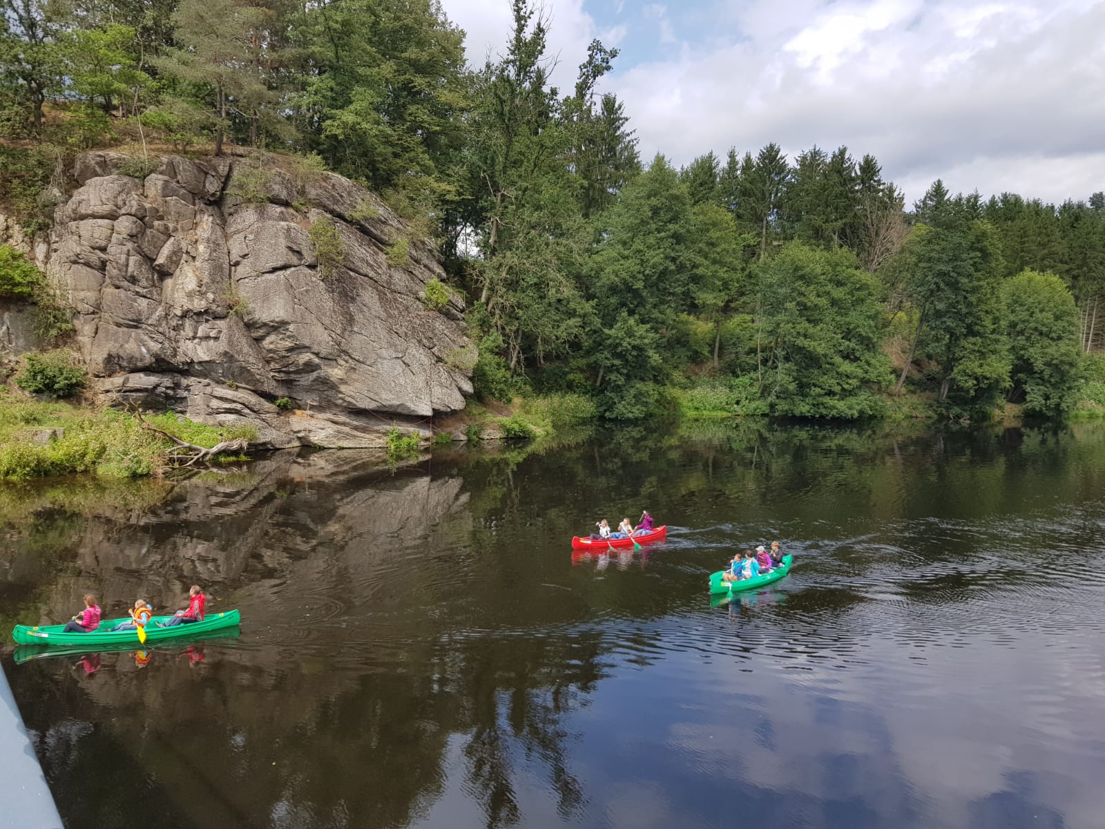 Kajaks gleiten über ruhiges Wasser vor steilen Felsen.