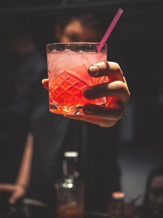 A glass of drink is held by one hand.