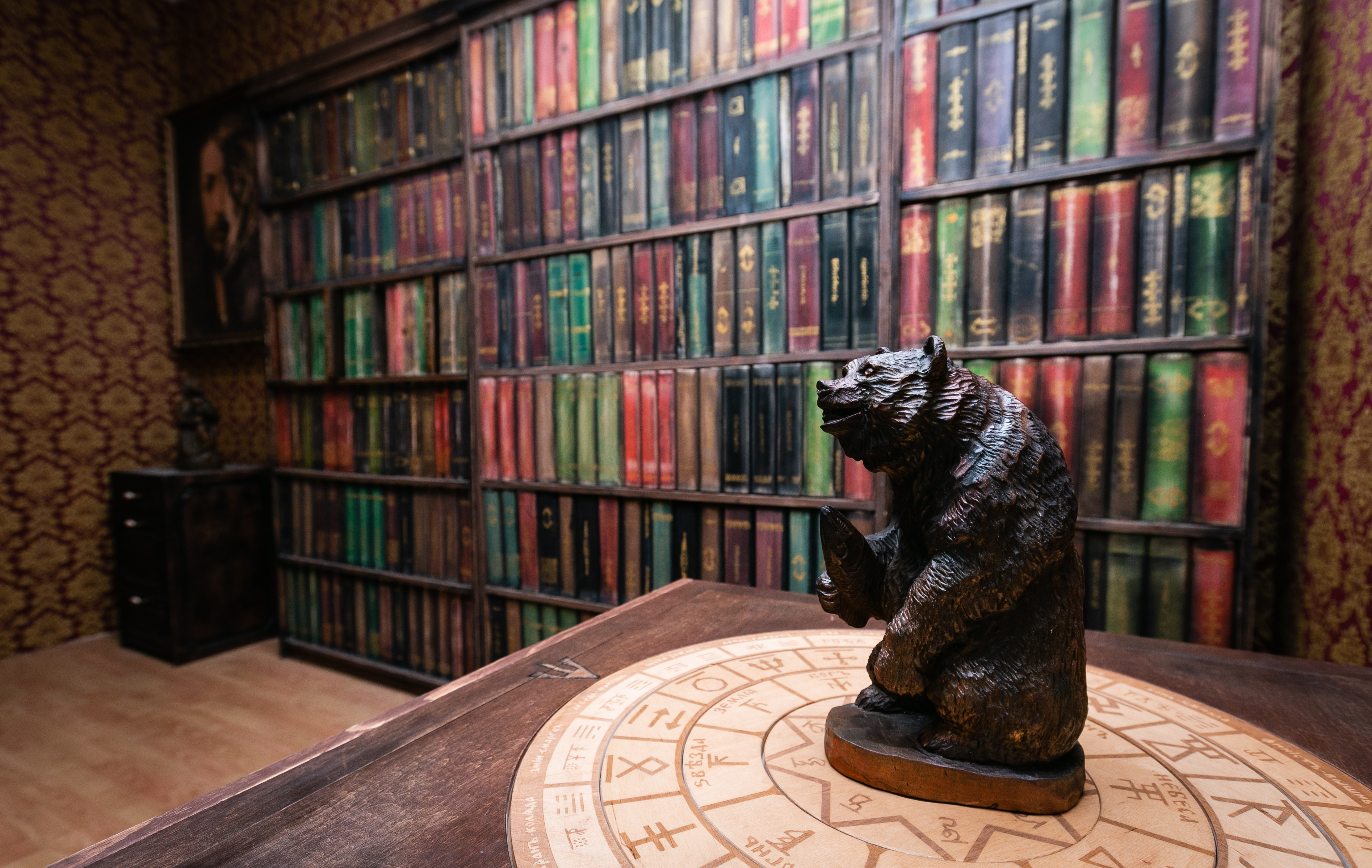 Bärstatue steht auf einem Tisch vor Bücherregalen.