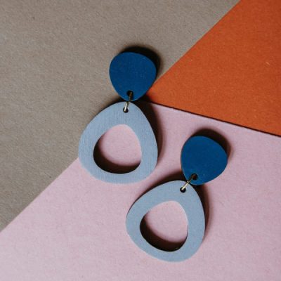 Colourful earrings lie on several layers of coloured paper.