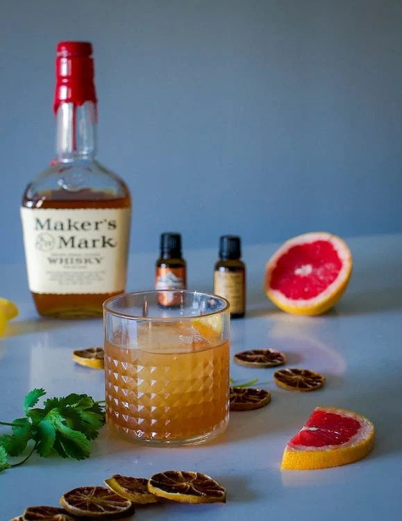 Whiskey glass with orange drink on table with ingredients