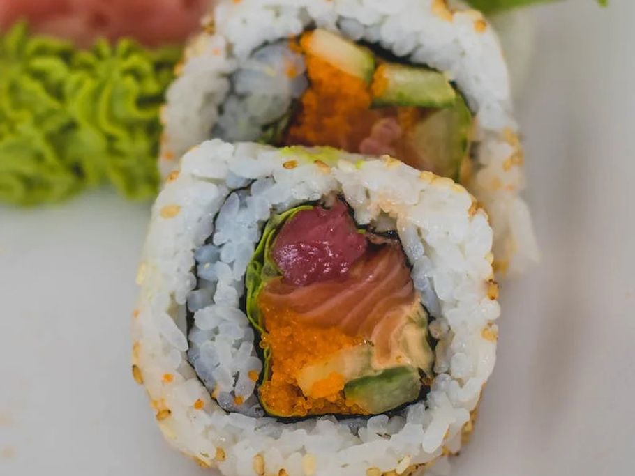 Sushi-Rollen liegen auf einem weißen Teller, appetitlich angerichtet.