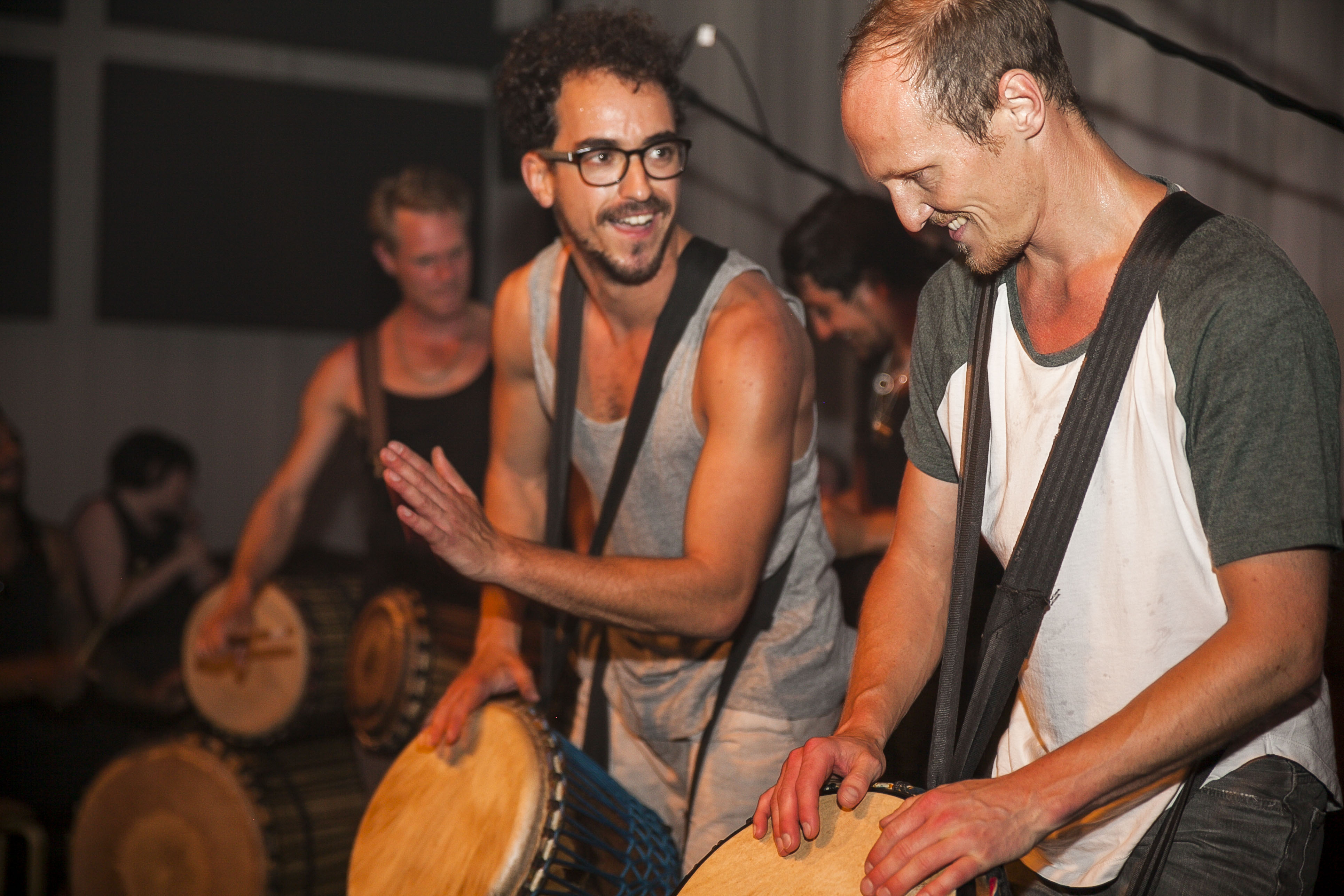 Drummers play rhythmically in a dark, festive room.