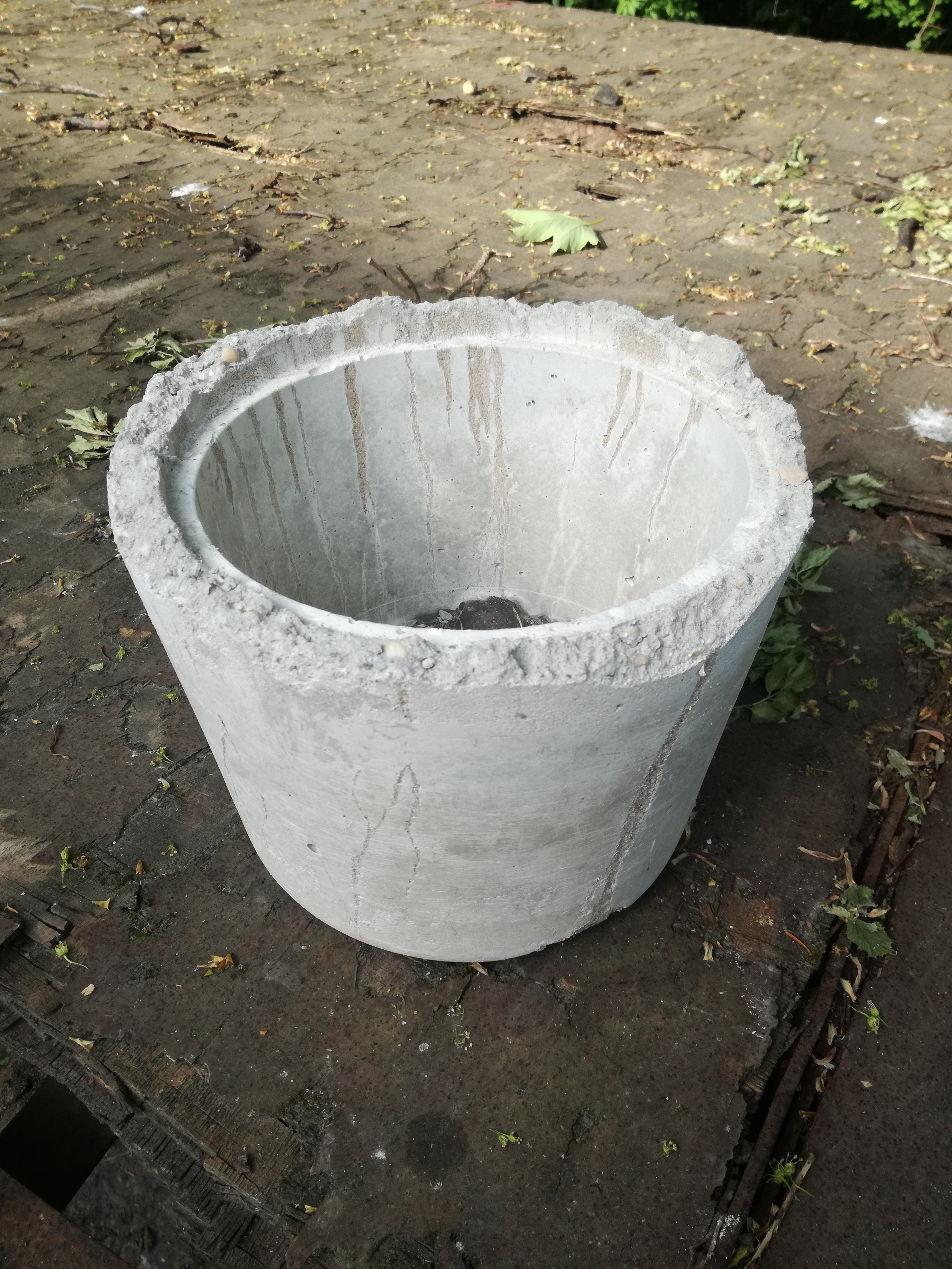 Betonbehälter steht leer auf dem Boden, umgeben von Erde.