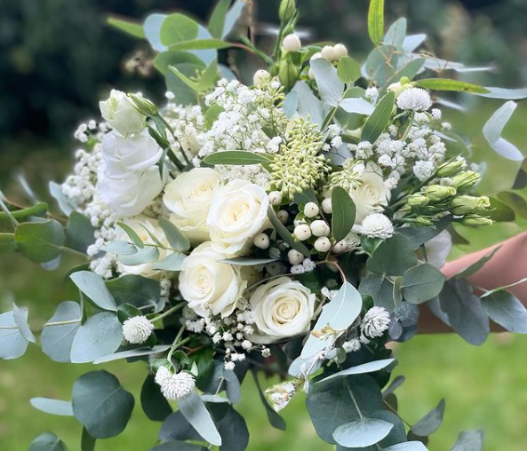 Weißer Blumenstrauß wird von einer Hand gehalten, im Freien.