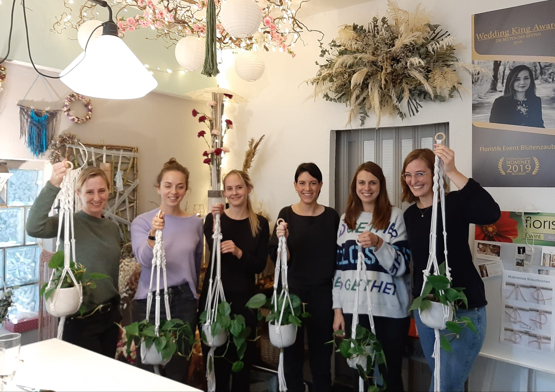 Sechs Frauen halten hängende Pflanzen in einem Laden.