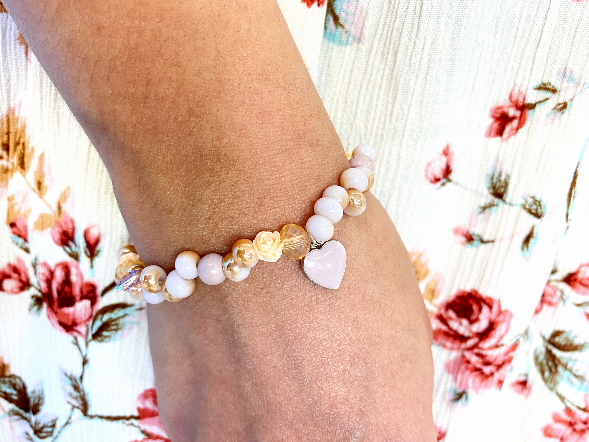 Armband auf Hand, zierlich geschmückt mit Rosen und Herz.