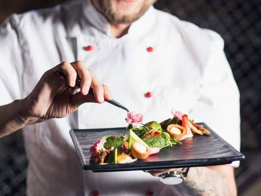 A chef is decorating a plate with delicious food.