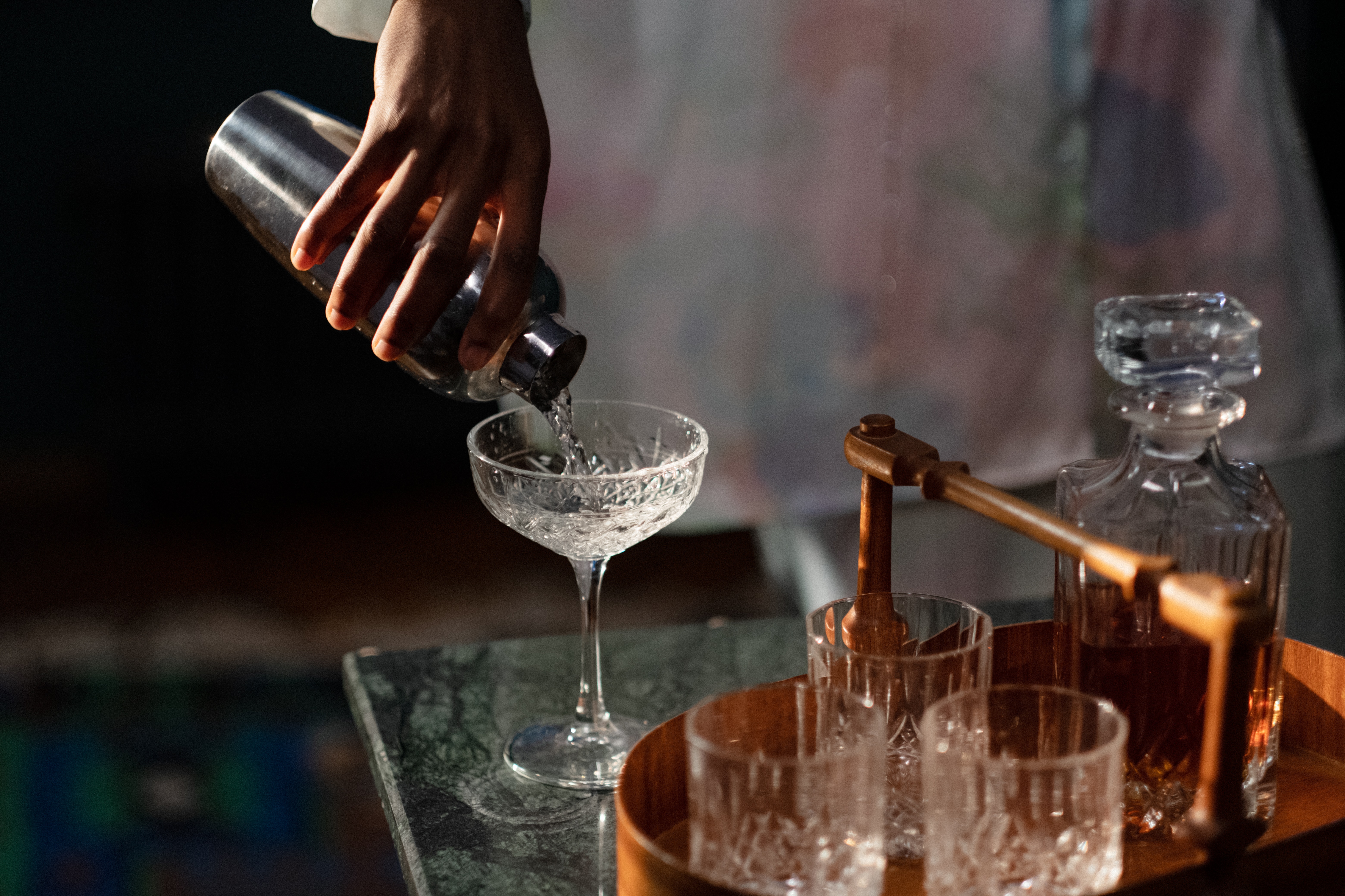 Ein Hand schüttelt Cocktails in ein Glas auf einem Tisch.