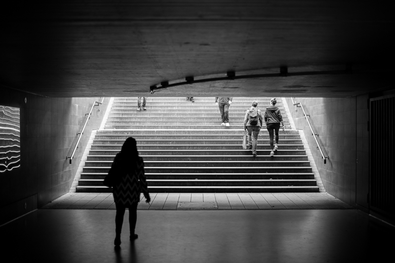 One person stands in a tunnel; others climb stairs.