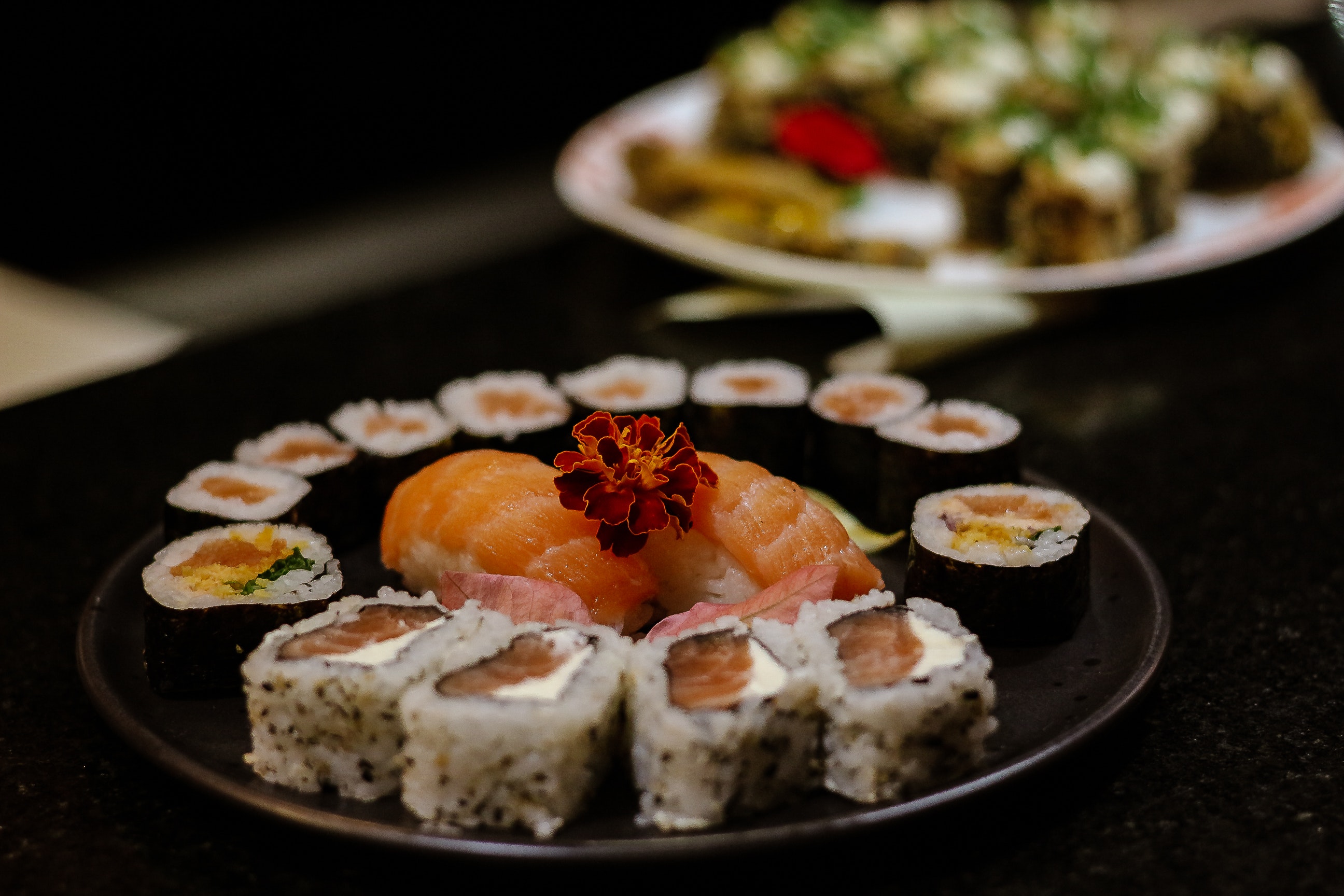 Sushi auf schwarzem Teller mit Blumen dekoriert, serviert.