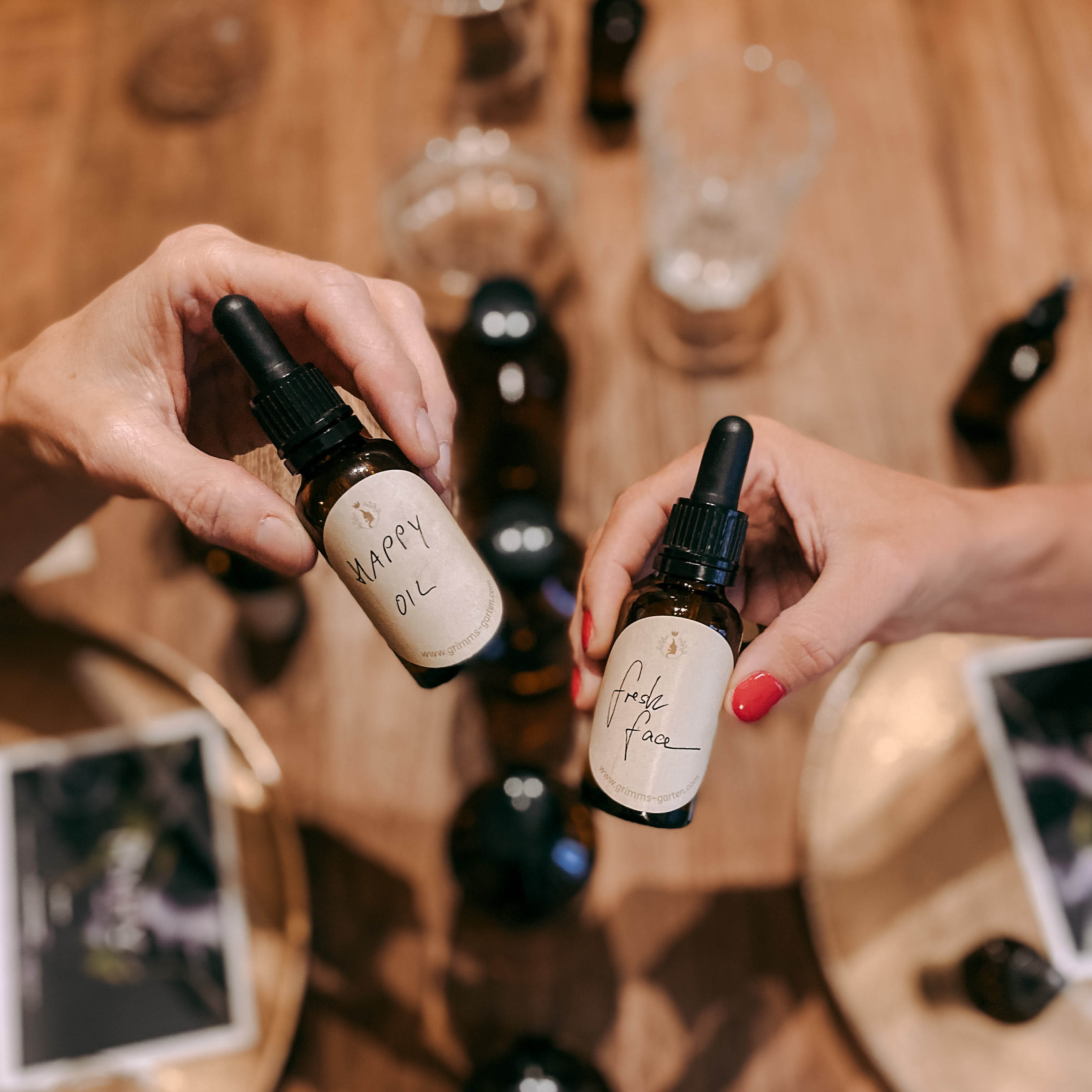 Two hands hold bottles of oils, the background is wood.