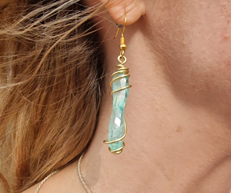Earrings with polished turquoise stone hang on the ear.