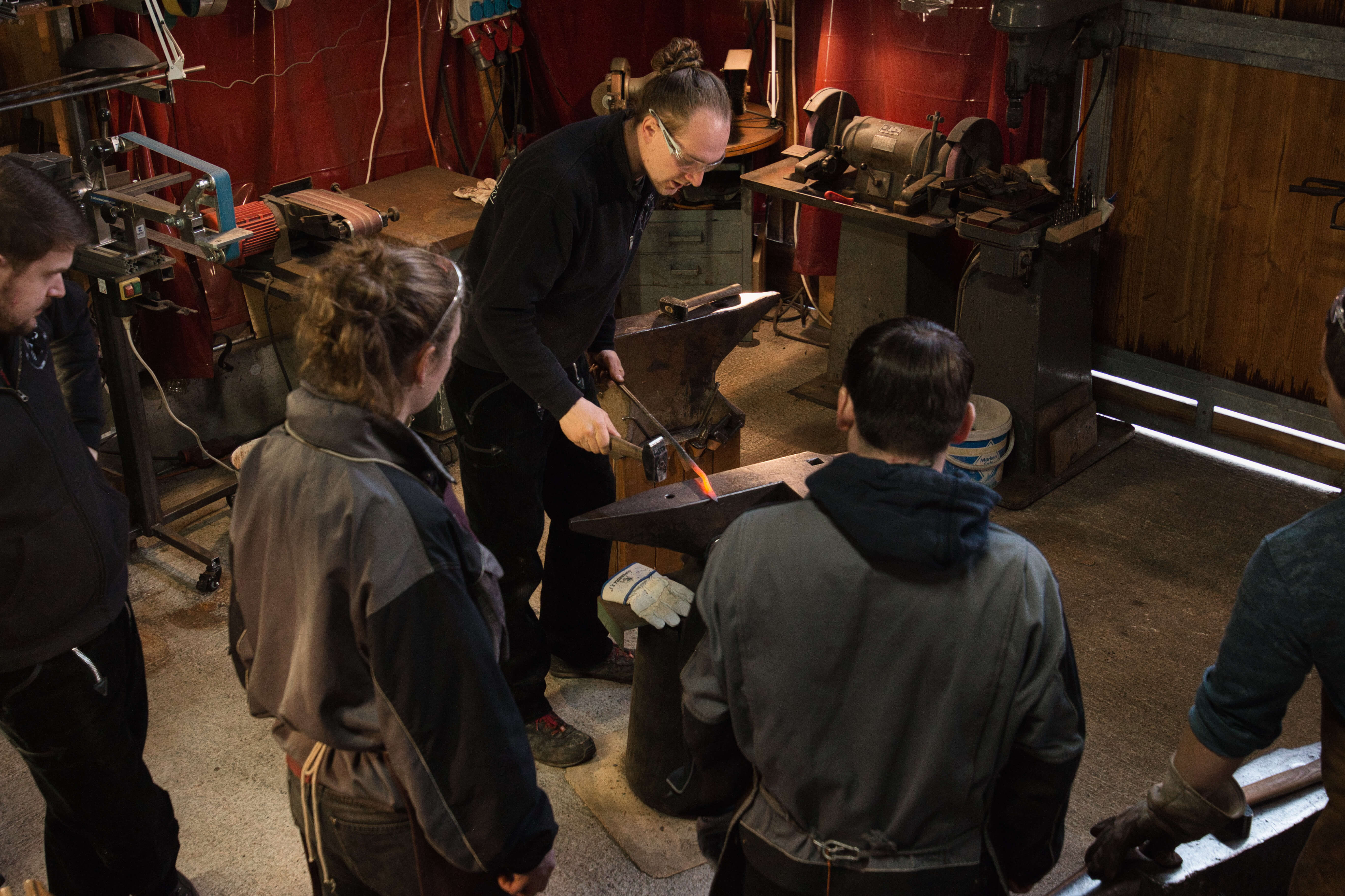 Blacksmith works with a glowing piece of metal on the anvil.