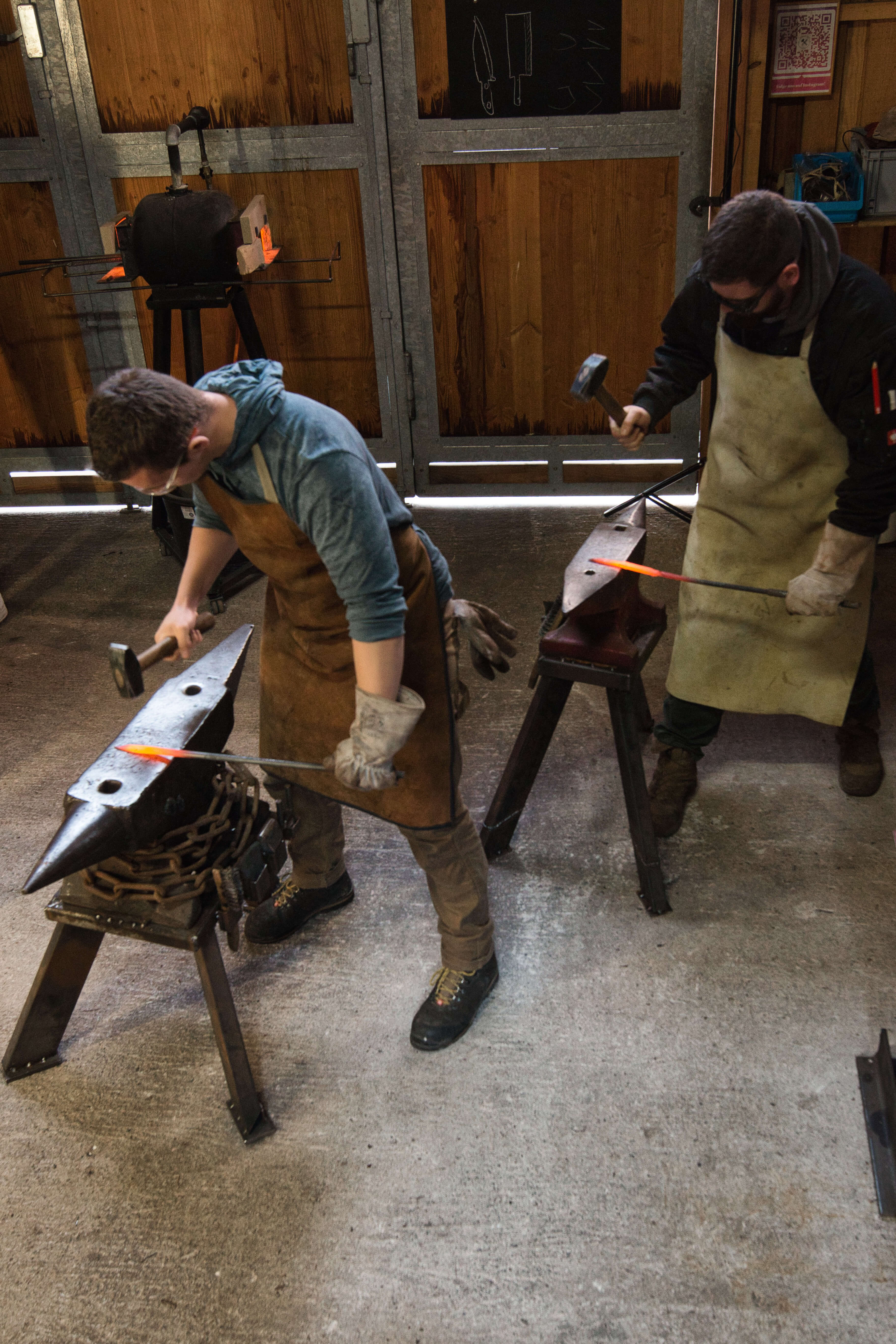 Blacksmith works with a hammer and glowing metal on the anvil.