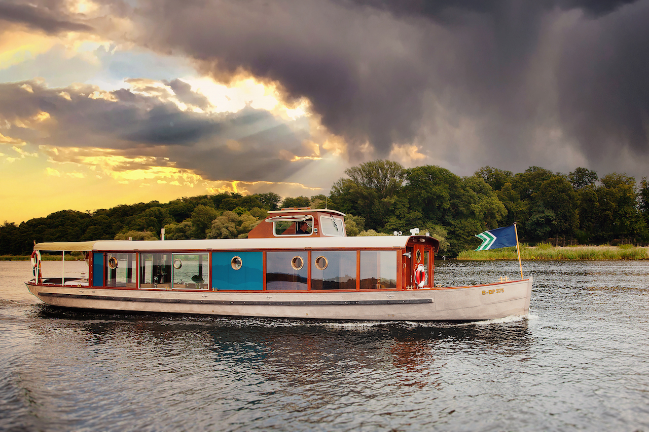 A boat sails on calm water under dramatic skies.