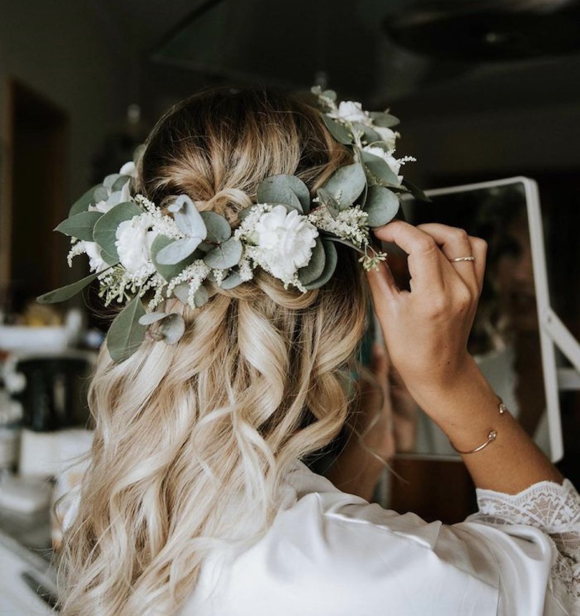 Hair decorated with a wreath of flowers, person looking in the mirror.