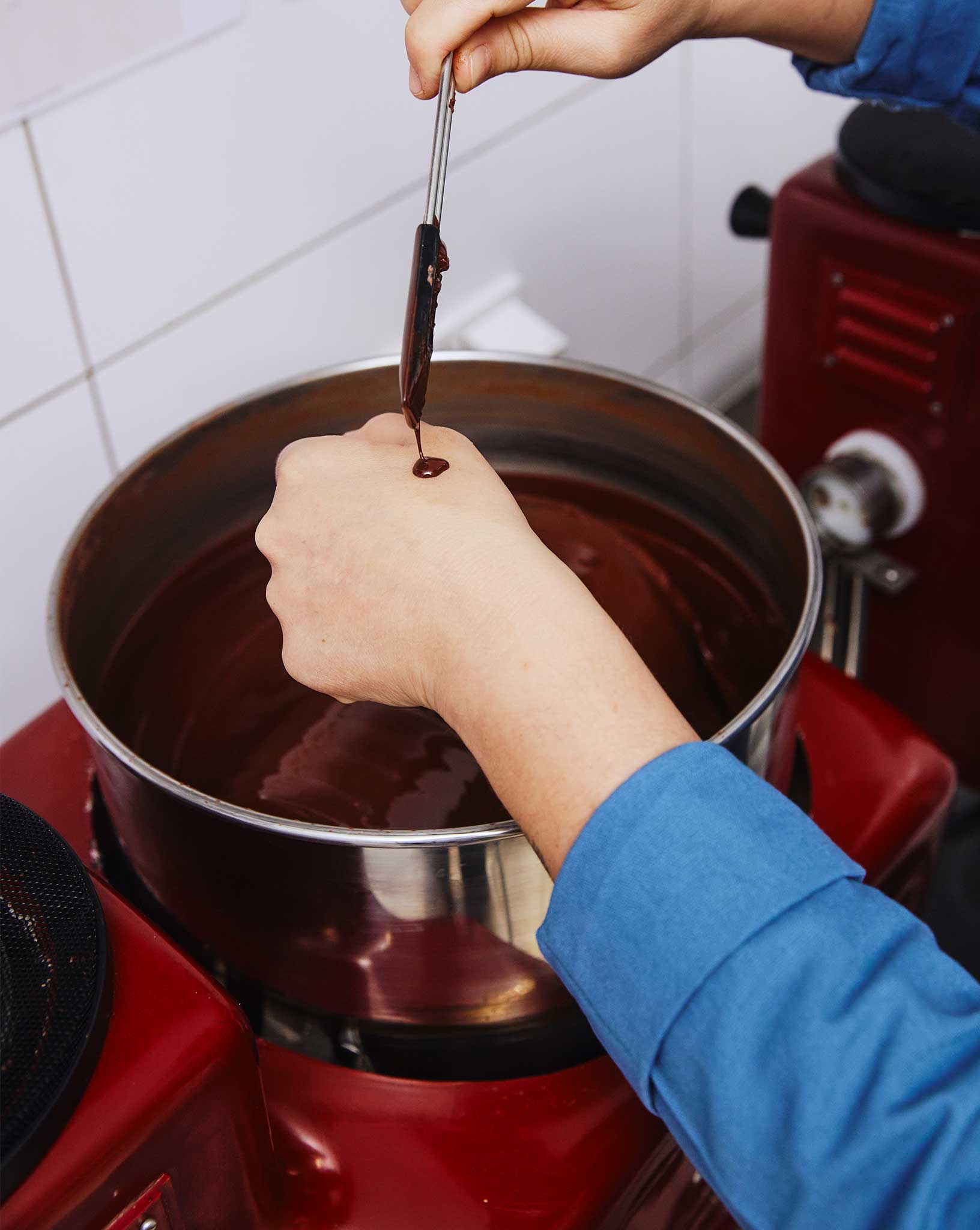 Hand drip chocolate from a spoon into a bowl.