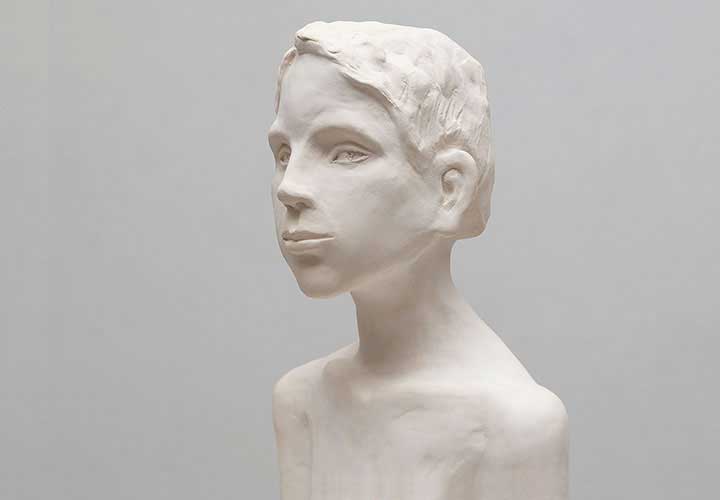 Sculpture of a head looking forward, neutral background.