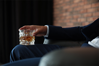 A man holds a whiskey glass in an elegant room.