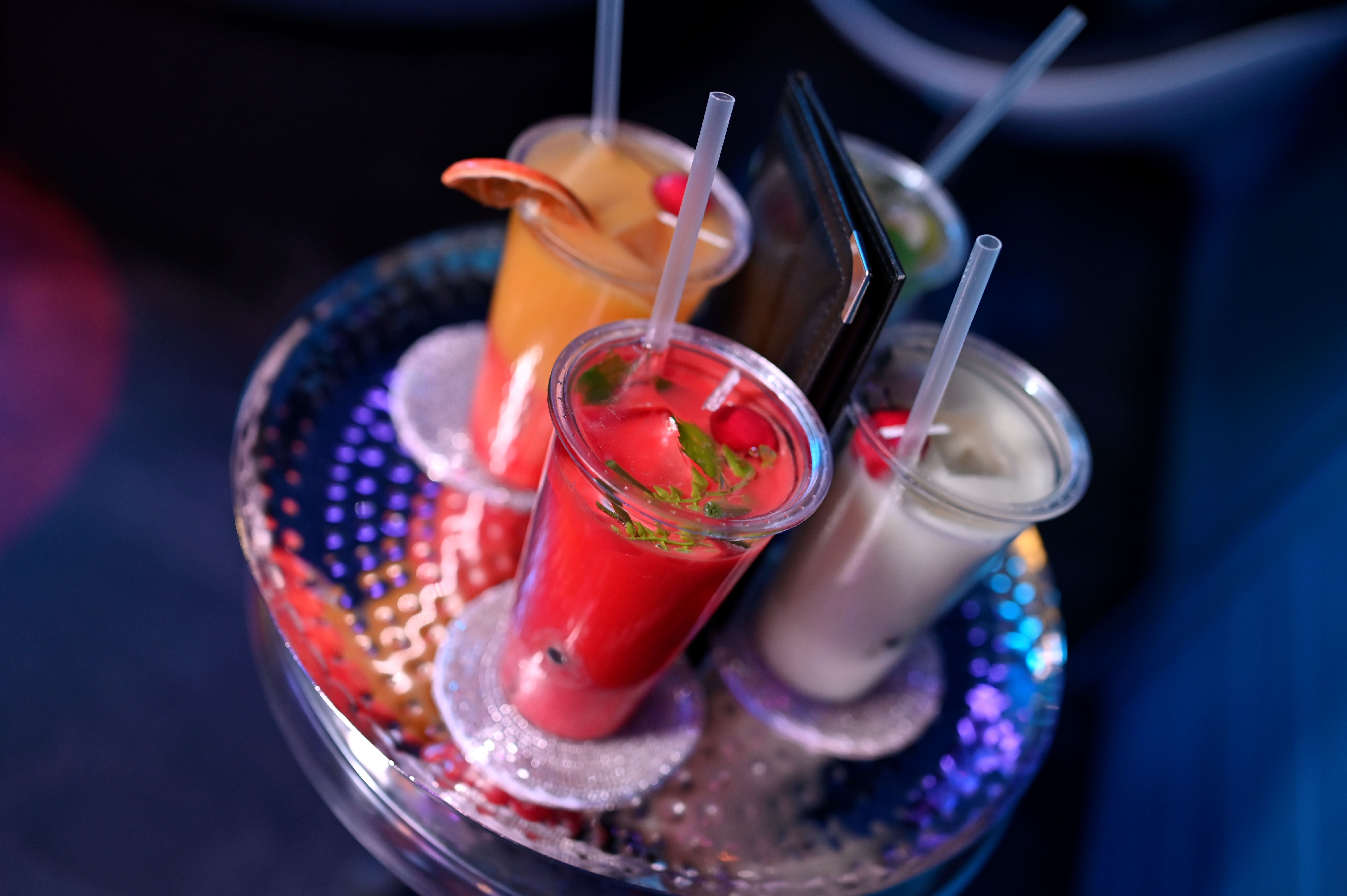 Four colorful cocktails sit on a sparkling tray.