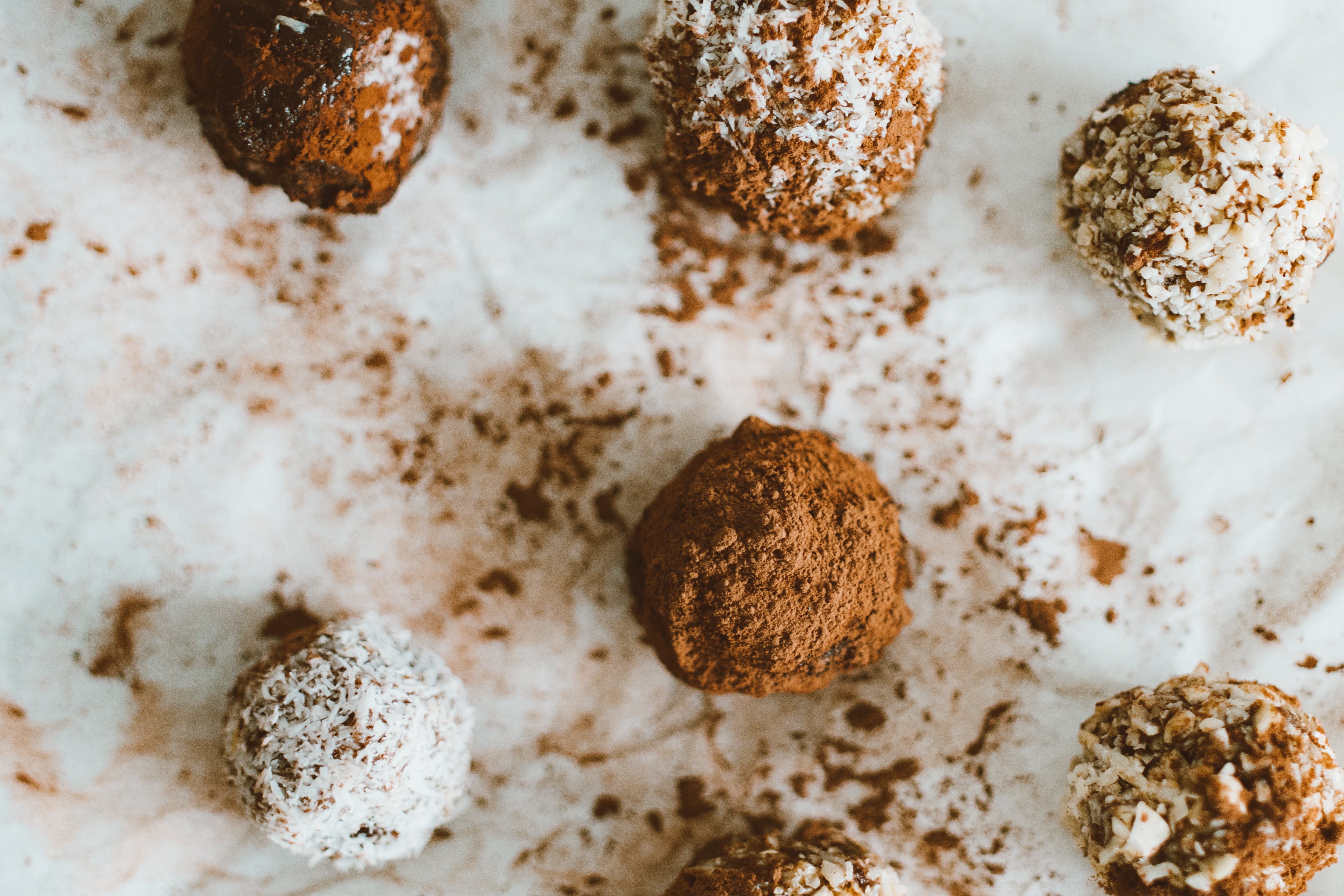 Chocolate balls are scattered on white paper.