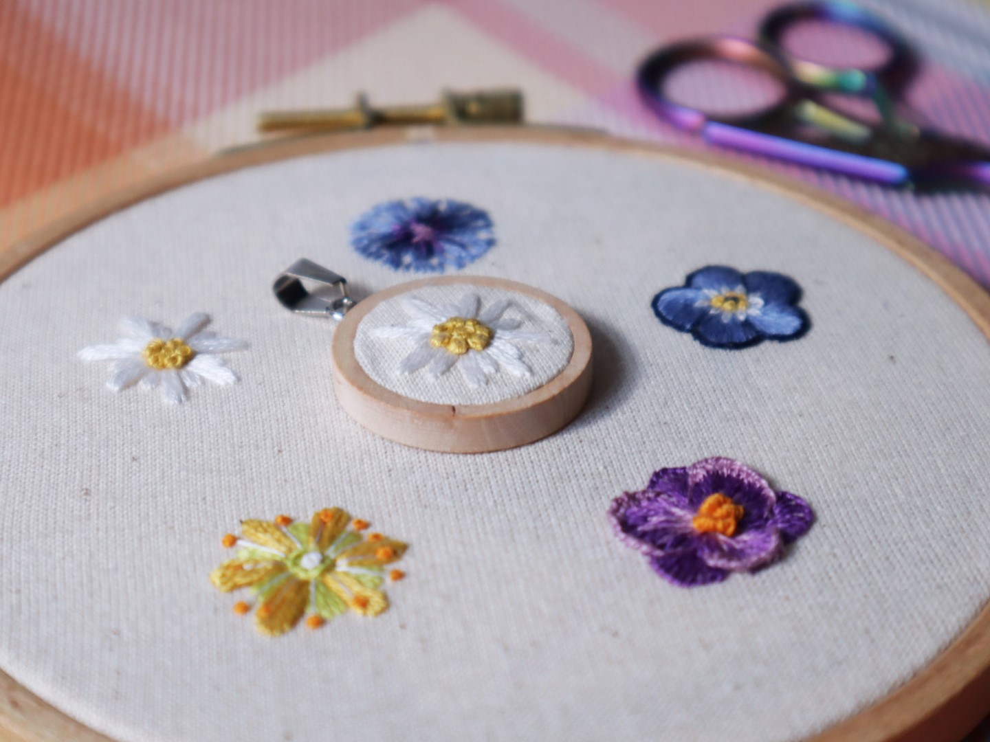 Gestickte Blumen in einem Rahmen mit einem Anhänger.