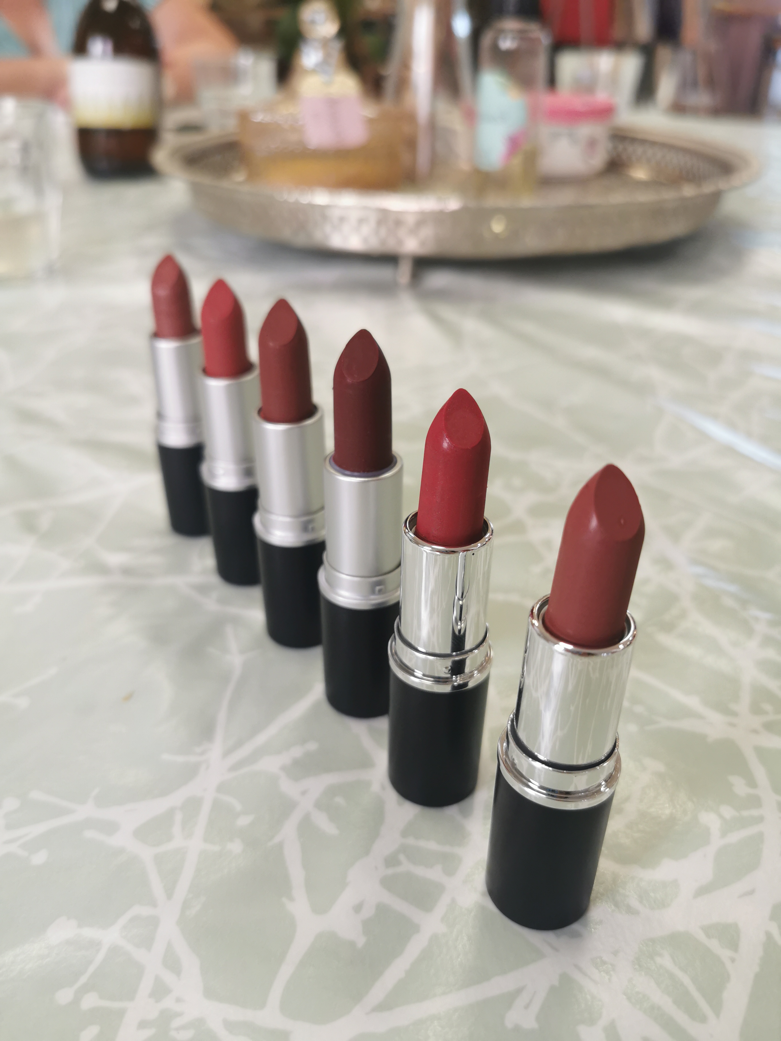 Sechs Lippenstifte stehen in einer Reihe auf einem Tisch.