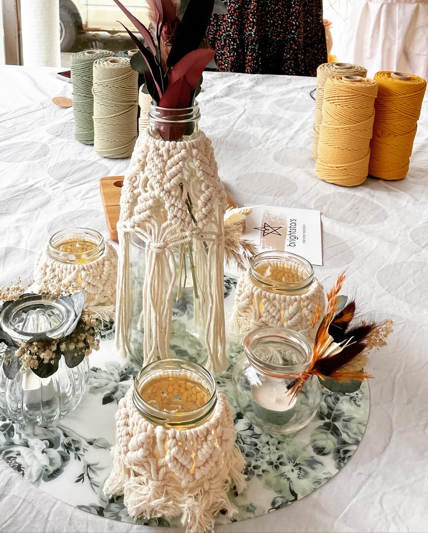 Vase with flowers surrounded by yarn and decoration.