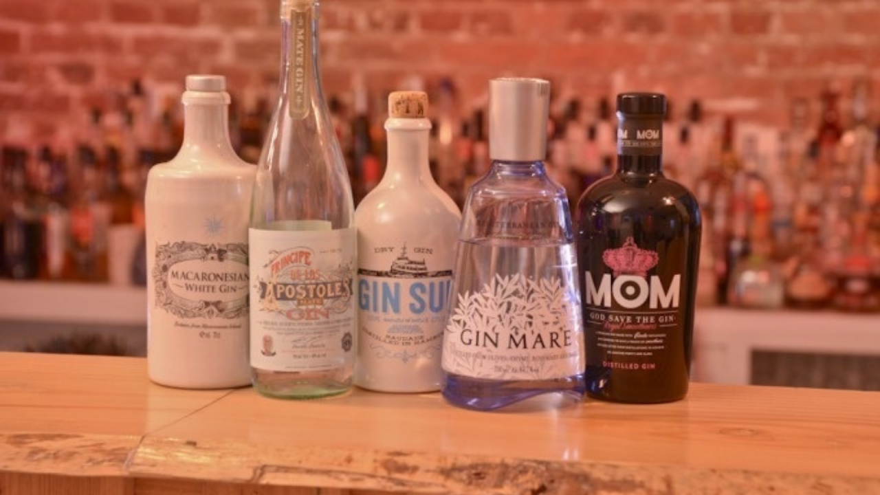 Fünf Gin-Flaschen stehen auf einer Holztheke.