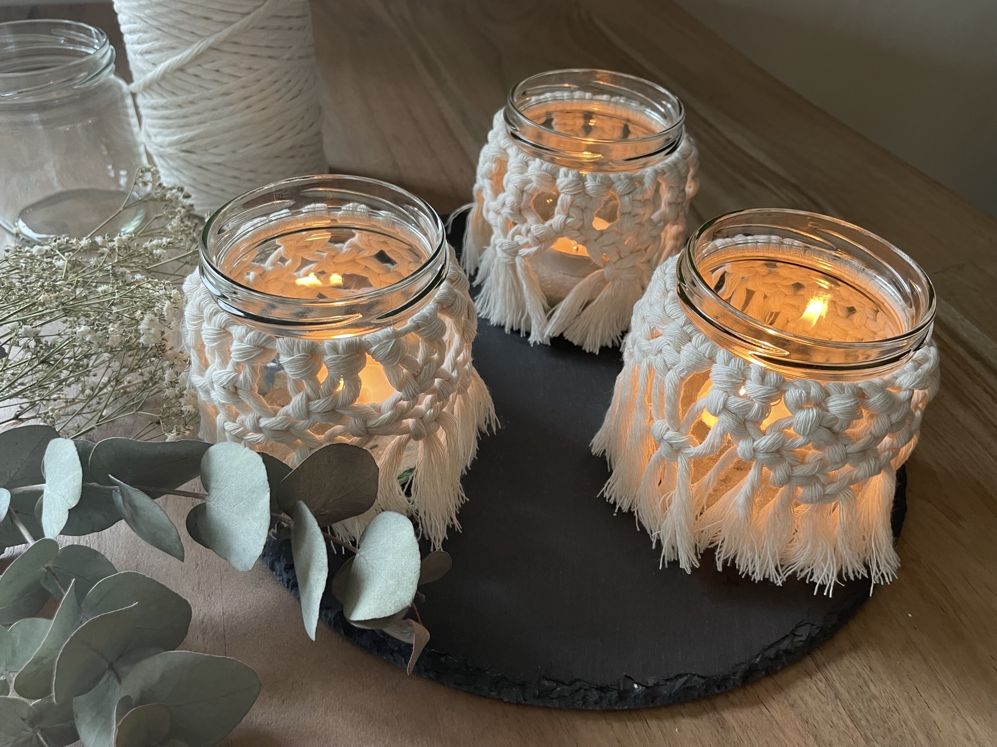 Three glass candle holders light up on a table.