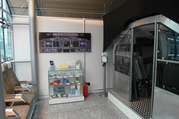 Schauplatz im Flughafen mit einem Cockpit-Simulator und Schaufenster.