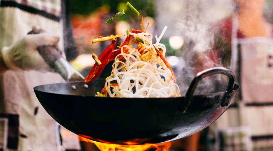 Wok mit Nudeln und Gemüse wird scharf angebraten.