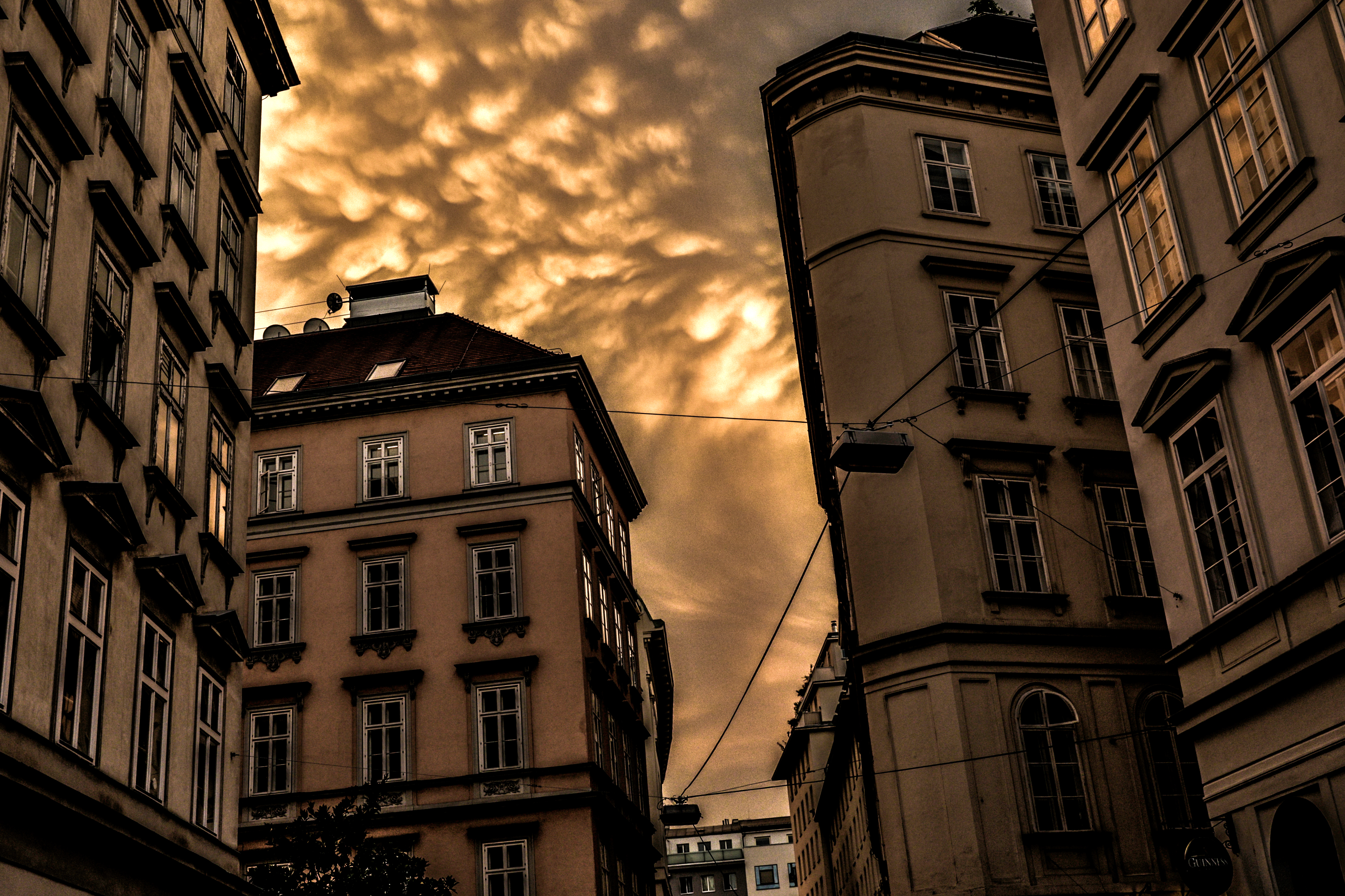 Buildings stand on a narrow street covered by clouds.